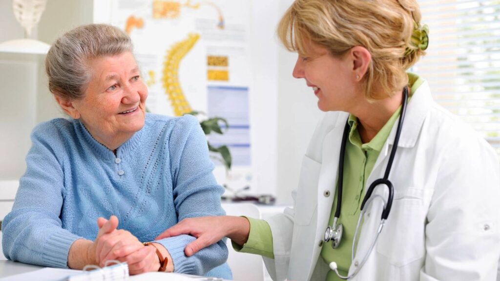 A doctor warmly consulting an elderly woman in a medical office.