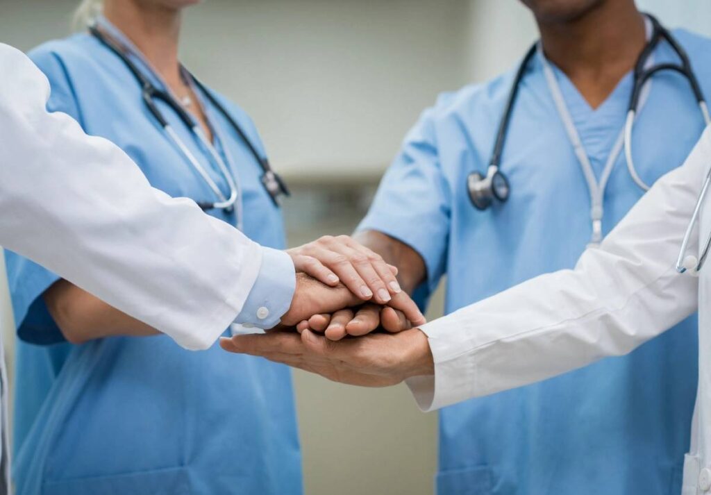 Healthcare professionals joining hands in a show of unity and support.