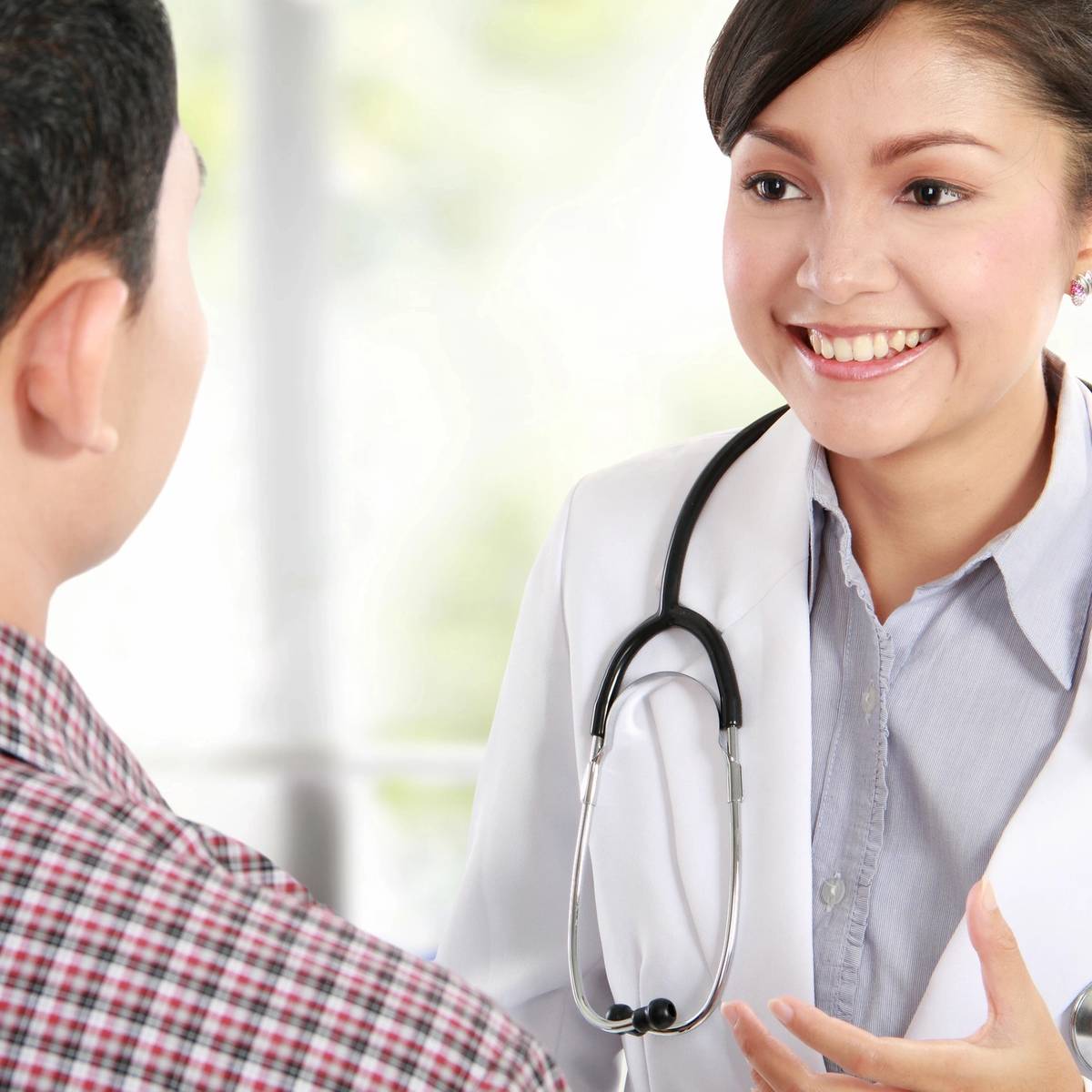 A female doctor attentively consulting with a patient in a bright office.