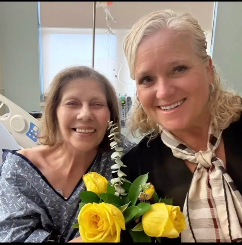 Two smiling women in hospital with yellow roses