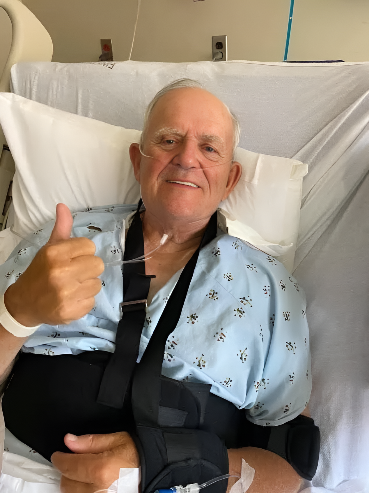 Elderly patient in hospital bed giving thumbs-up