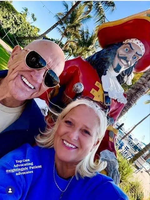 Two smiling people with large pirate statue