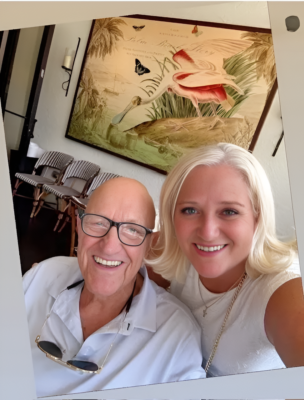 Two smiling people posing indoors with painting