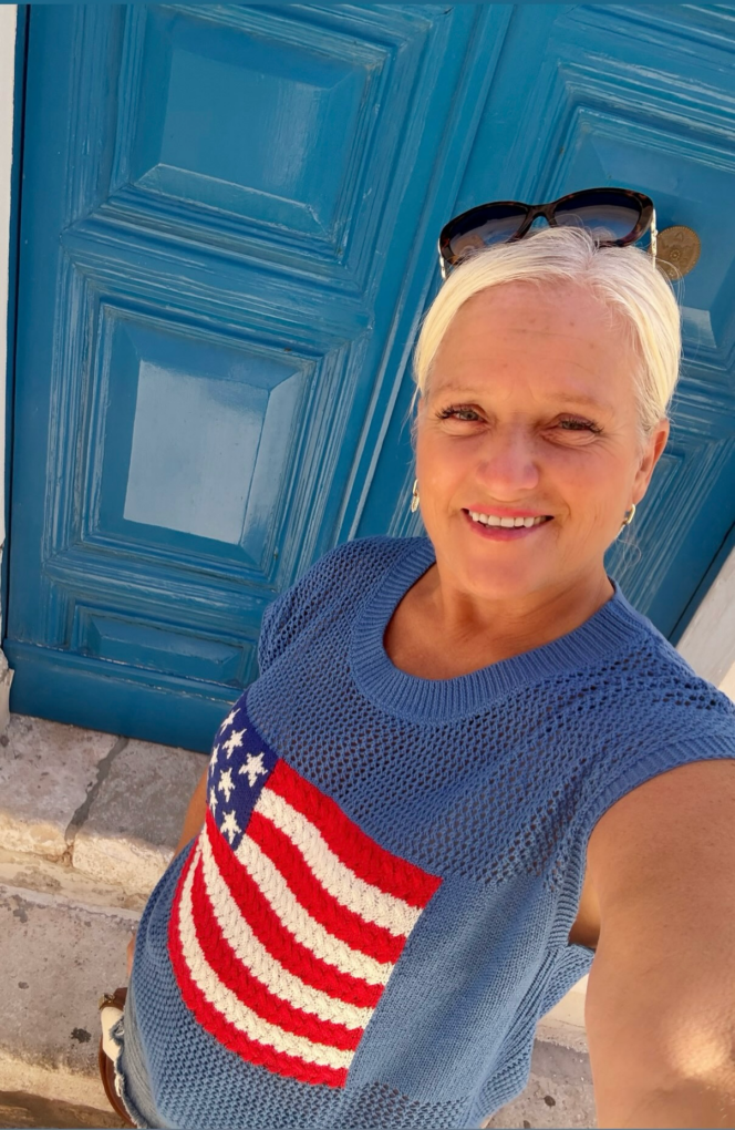 Woman smiling in a blue sweater with flag.