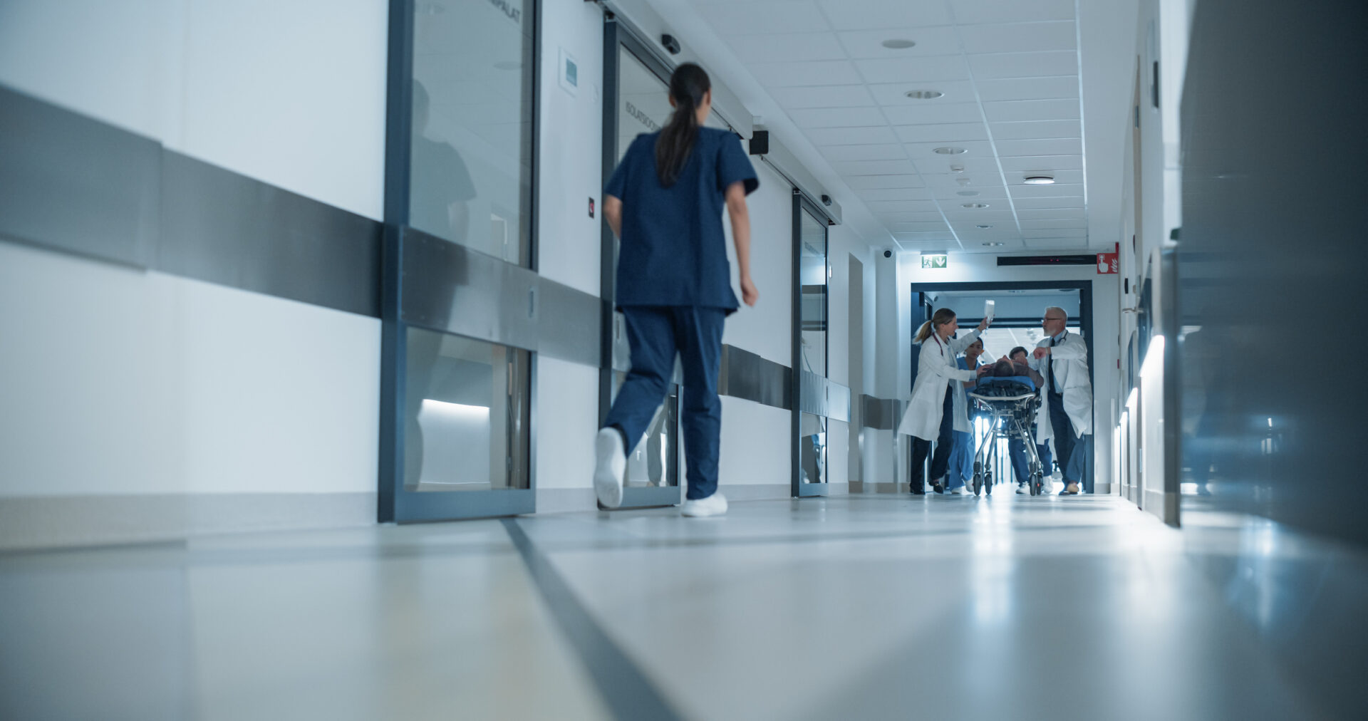 Medical team assisting patient down hallway.