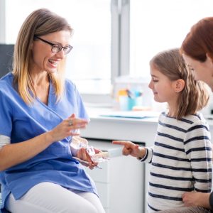 Pediatrician discussing medication with a young girl and her mother.